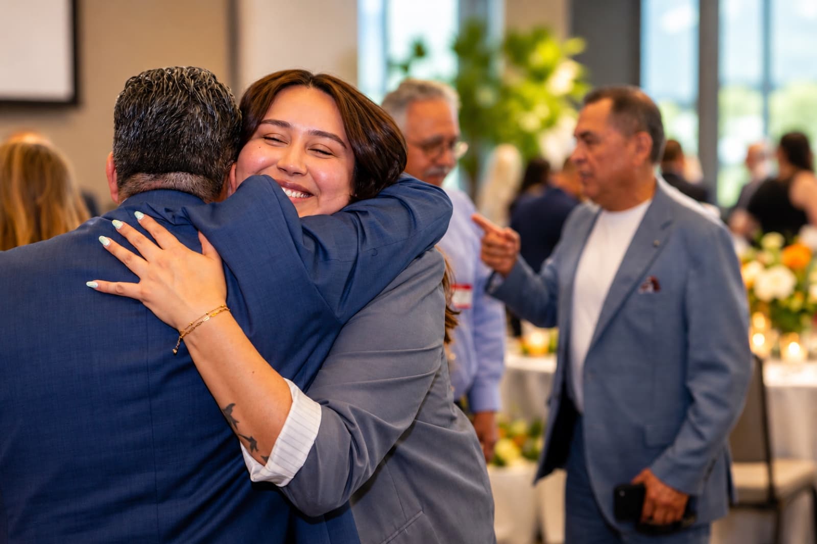 Two guests sharing a warm hug at the Wilmington Chamber of Commerce luncheon planned by ACCM Event Planning
